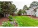 A well-maintained backyard with lush lawn, flower beds, mature trees and charming landscaping at 8588 S Woody Way, Highlands Ranch, CO 80126