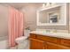 Bathroom featuring wood cabinets, a large mirror, a toilet, and a pink shower curtain at 8588 S Woody Way, Highlands Ranch, CO 80126