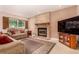 Comfortable living room featuring a brick fireplace, plush sofas, and a large window at 8588 S Woody Way, Highlands Ranch, CO 80126