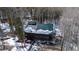 Aerial view of charming cabin with green roof and a garage with snow covered trees in the background at 9061 N Rex Ln, Conifer, CO 80433