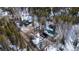 A high angle aerial shot reveals cabin with green roof surrounded by snow and bare trees in winter at 9061 N Rex Ln, Conifer, CO 80433