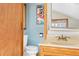 Cozy bathroom with blue walls and a vintage poster, a nice white toilet and sink with wooden fixtures at 9061 N Rex Ln, Conifer, CO 80433