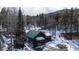 Charming log cabin with a green roof, surrounded by snow-covered landscape and tall trees at 9061 N Rex Ln, Conifer, CO 80433