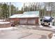 Large, rustic wooden garage with two bays, snow-covered roof, and an RV parked outside at 9061 N Rex Ln, Conifer, CO 80433