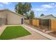 A tidy backyard features an artificial lawn, a concrete path, gravel, and a gray door to an attached garage at 3470 W Walsh Pl, Denver, CO 80219