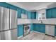 Corner view of the kitchen showing modern blue cabinets and stainless steel appliances with tile backsplash at 3470 W Walsh Pl, Denver, CO 80219
