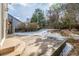 Concrete patio with steps leading to a snow-dusted backyard, bordered by a wooden fence and mature trees at 364 Willowick Cir, Highlands Ranch, CO 80129