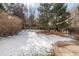 Fenced backyard partially covered in snow with mature trees and foliage at 364 Willowick Cir, Highlands Ranch, CO 80129