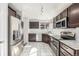 Modern kitchen with stainless steel appliances, dark wood cabinets, white subway tile backsplash, and white tile floors at 364 Willowick Cir, Highlands Ranch, CO 80129