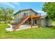 Green home's backyard boasts a wooden deck with stairs, leading to a patio and well-maintained lawn at 15545 Lipan St, Broomfield, CO 80023