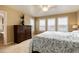 Bright bedroom with dresser, large bed, and window with plantation shutters at 9711 W Indore Dr, Littleton, CO 80128