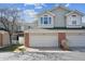 Two-story townhome with brick accents, a two-car garage, and manicured landscaping at 12860 E Dickensen Pl, Aurora, CO 80014