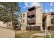 Apartment building with multiple balconies, landscaped lawn, and wood fencing for privacy at 9700 E Iliff Ave # 81, Denver, CO 80231