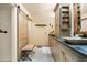 Bathroom with double sinks, wooden cabinetry, decorative mirrors, tiled shower, and a sliding barn door at 1181 E 130Th Pl, Thornton, CO 80241