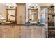 Bathroom with double sinks, wooden cabinetry, decorative mirrors, and tiled shower at 1181 E 130Th Pl, Thornton, CO 80241