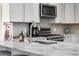Close up on a kitchen sink, stainless appliances, white marble countertop and patterned backsplash at 1181 E 130Th Pl, Thornton, CO 80241