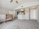 View of the living room with gray carpet and a chair, and a view of the kitchen at 8621 E Dry Creek Rd # 325, Englewood, CO 80112