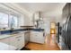 Modern kitchen with white cabinets, stainless steel appliances, and blue tile backsplash at 11845 W 30Th Pl, Lakewood, CO 80215