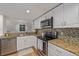 Bright kitchen features granite countertops, white cabinets, stainless steel appliances, and stylish backsplash at 10290 W Jewell Ave # B, Lakewood, CO 80232