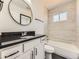 Modern bathroom with a white vanity, black countertop, and a tiled shower over bath at 655 S Osceola St, Denver, CO 80219