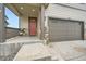 Front entry with a red door and a two car garage at 140 Racer St, Bennett, CO 80102