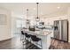 Kitchen island with pendant lighting and bar stool seating, stainless refrigerator and appliances at 140 Racer St, Bennett, CO 80102