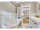 Bathroom featuring a clawfoot tub, white wainscoting, patterned wallpaper, and open doorway at 549 N Ogden St, Denver, CO 80218