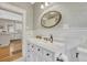 Bathroom with white vanity, round mirror, patterned wallpaper, and view into the kitchen at 549 N Ogden St, Denver, CO 80218