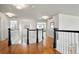 Bright upstairs hallway with hardwood floors, white walls, and dark railings and banisters at 8903 Edgewood St, Highlands Ranch, CO 80130