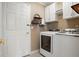 Practical laundry room with modern white washer and dryer, storage cabinets, and a door to outside at 8903 Edgewood St, Highlands Ranch, CO 80130