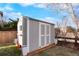 Exterior of a white and gray shed with double doors on a green lawn with landscaping at 8903 Edgewood St, Highlands Ranch, CO 80130