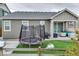 Backyard showcasing a trampoline, covered patio, artificial grass, and wood fence at 9694 Truckee St, Commerce City, CO 80022