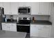 A modern kitchen features white cabinetry, a stainless steel microwave and oven, and gray countertops for a sleek, contemporary look at 9694 Truckee St, Commerce City, CO 80022