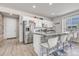 Bright kitchen featuring stainless steel appliances, white cabinetry, breakfast bar with stone accents, and hardwood floors at 9694 Truckee St, Commerce City, CO 80022
