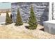 Landscaping featuring small trees and rock ground cover against a decorative stone wall at 9694 Truckee St, Commerce City, CO 80022