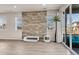 Bright living room with hardwood floors, stone accent wall, large windows, and sliding glass doors at 9694 Truckee St, Commerce City, CO 80022