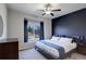 Comfortable main bedroom with a ceiling fan, navy blue accent wall, and backyard views at 8861 Ventura St, Commerce City, CO 80022