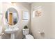 Half bathroom with a pedestal sink, toilet, mirror, and a window at 9804 Martin Luther King Blvd, Denver, CO 80238