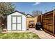 Grassy backyard features a storage shed with double doors, a privacy fence, mature trees, and a barbeque grill at 2841 W 27Th Ave, Denver, CO 80211