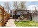 View of a backyard with a vine covered pergola, dining table, lush lawn, brick patio, and a grey house at 2841 W 27Th Ave, Denver, CO 80211