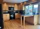 Bright kitchen with light wood cabinets, black appliances, hardwood floors, and a breakfast bar at 13187 E Bethany Pl, Aurora, CO 80014