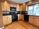 Kitchen with light wood cabinets, black appliances, hardwood floors, and a large window at 13187 E Bethany Pl, Aurora, CO 80014