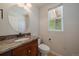 A well-lit half bathroom featuring granite countertops, a round mirror, and neutral paint at 11811 E Maplewood Ave, Englewood, CO 80111