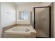 Bright bathroom featuring a soaking tub with tile surround and separate glass-enclosed shower at 11811 E Maplewood Ave, Englewood, CO 80111