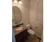 Compact half-bathroom with a sink, toilet, wood cabinets, and a decorative vanity mirror at 11811 E Maplewood Ave, Englewood, CO 80111