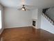 Bright living room featuring hardwood floors, a fireplace, a ceiling fan, and staircase access at 11811 E Maplewood Ave, Englewood, CO 80111