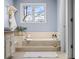 A relaxing soaking tub with beige tile surround in a bright bathroom at 5795 S Pagosa Way, Centennial, CO 80015