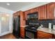 Kitchen features wooden cabinets, granite countertops, black appliances, and a tile backsplash at 1050 S Monaco Pkwy # 35, Denver, CO 80224