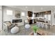Open-concept living space with an electric fireplace, gray accent chairs, and dark wood kitchen at 46550 Avery Ln, Bennett, CO 80102