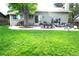 Expansive backyard with mature trees, a patio area for outdoor dining, and lush green grass at 1936 S Poplar St, Denver, CO 80224